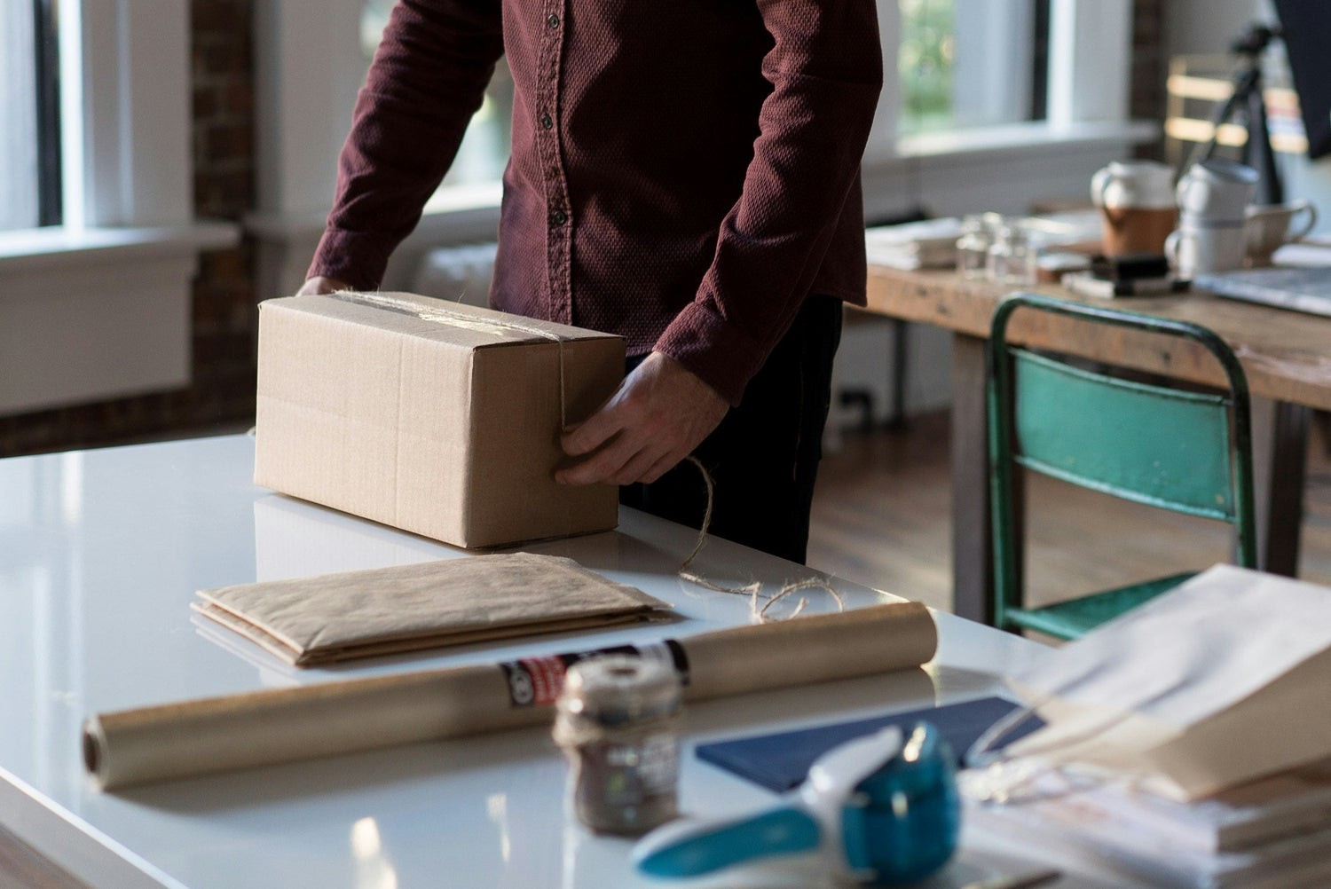 Person in a home office setting wrapping a parcel.